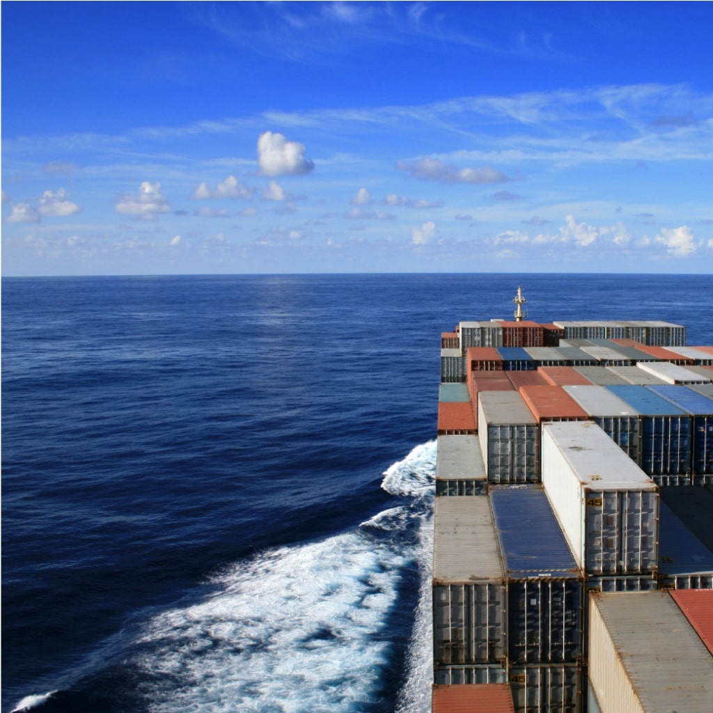 Imagen de un barco cargado de contenedores navegando en alta mar.